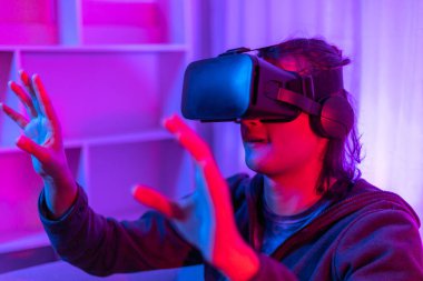 Sanal gerçeklik gözlüğü takan adam heyecan verici bir 3 boyutlu oyun oynuyor, Bluetooth Uzaktan Kumanda, VR, Gelecek Oyunları, Gadget, Teknoloji, Kırmızı ve Mavi arka plan, VR oyun konsepti.