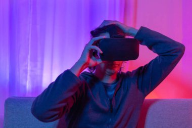 Sanal gerçeklik gözlüğü takan adam heyecan verici bir 3 boyutlu oyun oynuyor, Bluetooth Uzaktan Kumanda, VR, Gelecek Oyunları, Gadget, Teknoloji, Kırmızı ve Mavi arka plan, VR oyun konsepti.