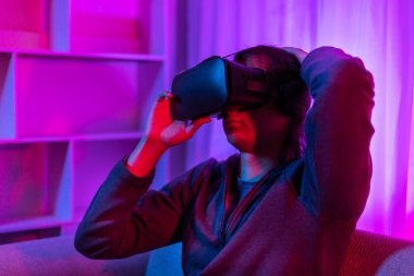 Sanal gerçeklik gözlüğü takan adam heyecan verici bir 3 boyutlu oyun oynuyor, Bluetooth Uzaktan Kumanda, VR, Gelecek Oyunları, Gadget, Teknoloji, Kırmızı ve Mavi arka plan, VR oyun konsepti.