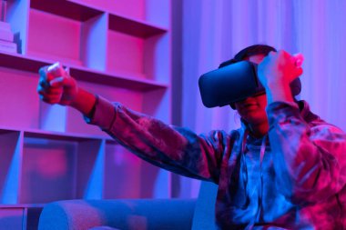 İnsan sanal gerçeklik gözlüğü takar ve eğlenceli, VR, Future Games, Technology, Red and Blue Controller, Touch Controller, Bluetooth Uzaktan Kumanda, VR oyun konsepti ile oyun oynamak için joystick kullanır.