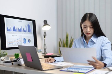 Asya 'daki pazarlama şefi şirketin finansal büyüme grafiğini analiz ediyor. Kişisel bilgisayarları iş için kullanıyor, ev kavramı üzerine çalışıyor..