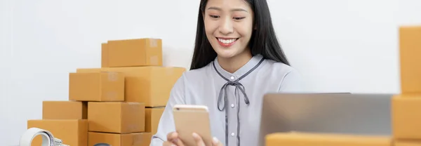 Young Asian women are selling products online and are using mobile phones to chat with customers to confirm orders, Selling products online or doing freelance work at home concept.