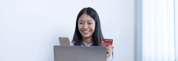 Young women are happy to shop online and hold credit cards to make payments over the Internet in the laptop or phone, Online shopping and Credit card payment.