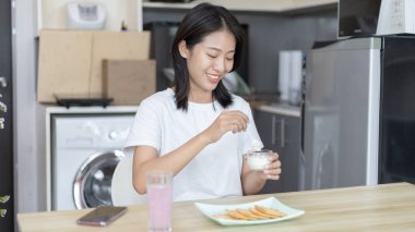 Yarı Japon kadın kahvaltıda mısır gevreğiyle yoğurt yiyor, sağlıklı yiyecekler ve sindirim sistemi bakımı en popüler ve en kolay kahvaltılık yiyecekler..