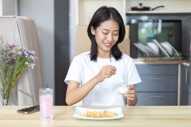 Yarı Japon kadın kahvaltıda mısır gevreğiyle yoğurt yiyor, sağlıklı yiyecekler ve sindirim sistemi bakımı en popüler ve en kolay kahvaltılık yiyecekler..