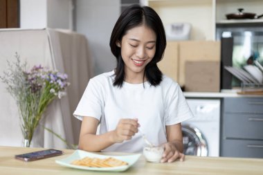 Yarı Japon kadın kahvaltıda mısır gevreğiyle yoğurt yiyor, sağlıklı yiyecekler ve sindirim sistemi bakımı en popüler ve en kolay kahvaltılık yiyecekler..