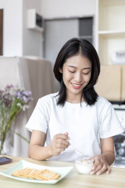 Yarı Japon kadın kahvaltıda mısır gevreğiyle yoğurt yiyor, sağlıklı yiyecekler ve sindirim sistemi bakımı en popüler ve en kolay kahvaltılık yiyecekler..