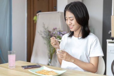 Yarı Japon kadın kahvaltıda mısır gevreğiyle yoğurt yiyor, sağlıklı yiyecekler ve sindirim sistemi bakımı en popüler ve en kolay kahvaltılık yiyecekler..