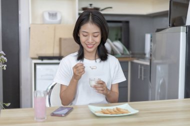 Yarı Japon kadın kahvaltıda mısır gevreğiyle yoğurt yiyor, sağlıklı yiyecekler ve sindirim sistemi bakımı en popüler ve en kolay kahvaltılık yiyecekler..
