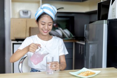 Asyalı kadın kahvaltısını kraker (sağlıklı tam tahıl) ve meyve suyu ile yer, telefonunuzu ya da cep telefonunuzu sabah haberlerini aramak için kullanın, apartman zemininde küçük bir oda, uyandırma aktiviteleri.