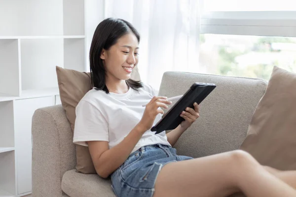 Asyalı Bir Kadın Oturma Odasında Kanepede Tablet Kullanarak Oturuyor Tablet — Stok fotoğraf