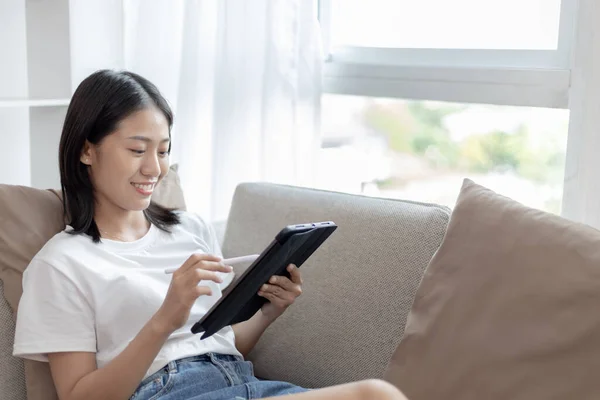 Asyalı Bir Kadın Oturma Odasında Kanepede Tablet Kullanarak Oturuyor Tablet — Stok fotoğraf