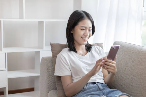 Asiatin Sitzt Mit Smartphone Auf Sofa Wohnzimmer Blick Auf Tablet — Stockfoto