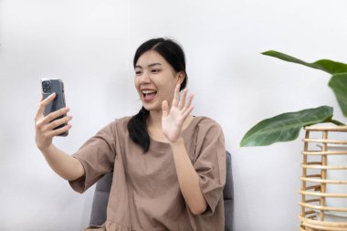 Genç Asyalı bir kadın cep telefonunu kullanarak arkadaşlarıyla konuşur, cep telefonu teknolojisini kullanır, eğlenir ya da dinlenir, uzun bir hafta sonu evde kalır, mutlu bir yaşam tarzı sürdürür..