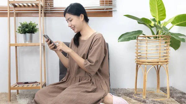 Genç Asyalı kadın cep telefonunu arkadaşlarıyla sohbet etmek ya da konuşmak, cep telefonu teknolojisini kullanarak eğlenmek ya da dinlenmek, hafta sonu evde kalmak, mutlu bir yaşam tarzı....