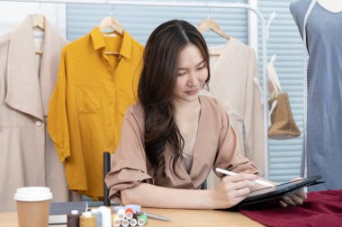 Tasarım stüdyosundaki tablet, moda tasarımcısı, yaratıcılık ve fikirler, manken, tişört çizimi, renk düzeni, giysi aksesuarları aracılığıyla profesyonel kadın tasarımcı kıyafetleri tasvir etme, bağımsız çalışma.
