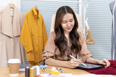 Tasarım stüdyosundaki tablet, moda tasarımcısı, yaratıcılık ve fikirler, manken, tişört çizimi, renk düzeni, giysi aksesuarları aracılığıyla profesyonel kadın tasarımcı kıyafetleri tasvir etme, bağımsız çalışma.