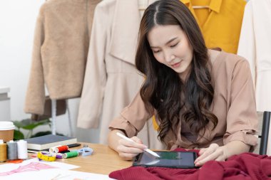 Professional female designer sketching outfits through tablet in the design studio, Fashion designer, Creativity and ideas, Mannequin, Shirt sketch, Color scheme, Garment accessories ,work independently.