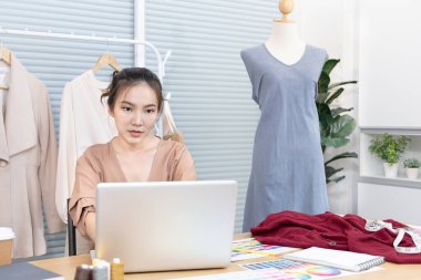 Professional female designer sketches of clothes through laptop in the design studio, Fashion designer, Creativity and ideas, Mannequin, Shirt sketch, Color scheme, Garment accessories ,Freelance.