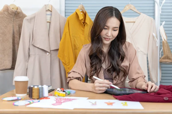 Professional female designer sketching outfits through tablet in the design studio, Fashion designer, Creativity and ideas, Mannequin, Shirt sketch, Color scheme, Garment accessories ,work independently.