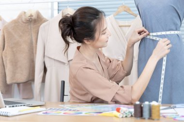 Profesyonel kadın tasarımcılar, stüdyodaki gömlek mankenleri, moda tasarımcıları, yaratıcılık ve fikirler, manken eskizi, renk şeması, giysi aksesuarları etrafında mezura kullanırlar..