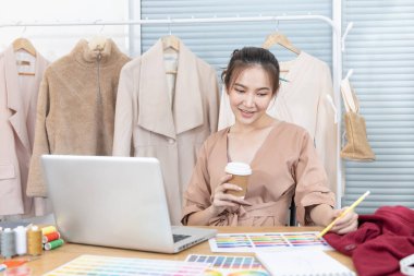 Professional designer sits at her desk thinking about fashion design ideas in her studio, Fashion designer, Creativity and ideas, Mannequin, Shirt sketch, Color scheme, Garment accessories.