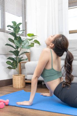 Slim Asian woman doing yoga meditation at home, Stretching the muscles of the body and practicing proper breathing, Yoga studio, Wearing sportswear, Healthy lifestyle, Exercise concept.