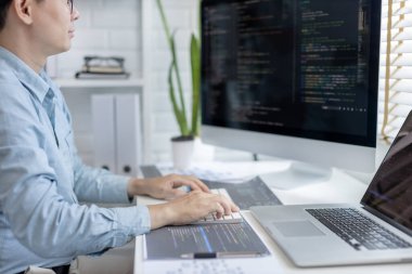 Profesyonel geliştirme programcıları, bilgisayar-laptop-tablet gibi çalışma ekipmanlarıyla bir masada otururlar. Web sitesi, HTML, javascript, Yazılım üzerinde çalışmak veya kod yazmak için.