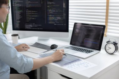 Professional development programmers are laying out a structure or draft on paper in preparation for coding on a computer, Write information or code for the website,  HTML, javascript, Software.
