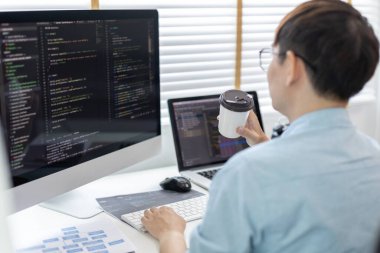 Profesyonel geliştirme programcıları özel bir ofiste kahve yudumluyor, bir bilgisayarda kodlama veya programlama, web sitesi için bilgi veya kod yazma, HTML, Javascript, Yazılım üzerinde çalışıyor.