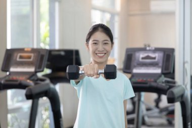 Beautiful and shapely Asian woman working out in the gym, Play exercise machine treadmill, Dumbbell, stretching, Hanging bar, Barbell, Cardio, Stretch, Woman warming up in the gym, Jump rope.