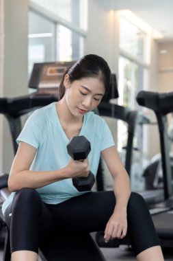 Beautiful and shapely Asian woman working out in the gym, Play exercise machine treadmill, Dumbbell, stretching, Hanging bar, Barbell, Cardio, Stretch, Woman warming up in the gym, Jump rope.