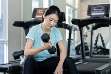 Beautiful and shapely Asian woman working out in the gym, Play exercise machine treadmill, Dumbbell, stretching, Hanging bar, Barbell, Cardio, Stretch, Woman warming up in the gym, Jump rope.