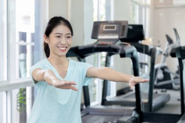 Beautiful and shapely Asian woman working out in the gym, Play exercise machine treadmill, Dumbbell, stretching, Hanging bar, Barbell, Cardio, Stretch, Woman warming up in the gym, Jump rope.