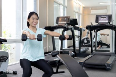 Beautiful and shapely Asian woman working out in the gym, Play exercise machine treadmill, Dumbbell, stretching, Hanging bar, Barbell, Cardio, Stretch, Woman warming up in the gym, Jump rope.
