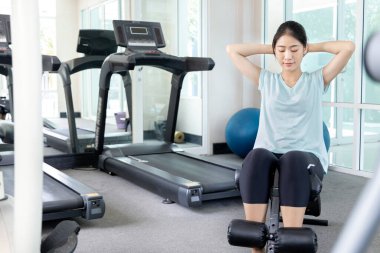 Beautiful and shapely Asian woman working out in the gym, Play exercise machine treadmill, Dumbbell, stretching, Hanging bar, Barbell, Cardio, Stretch, Woman warming up in the gym, Jump rope.