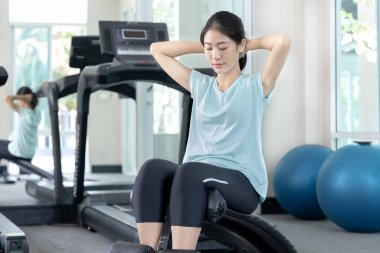 Beautiful and shapely Asian woman working out in the gym, Play exercise machine treadmill, Dumbbell, stretching, Hanging bar, Barbell, Cardio, Stretch, Woman warming up in the gym, Jump rope.