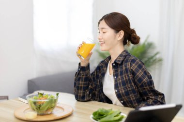 Beautiful woman eating fresh salad and watch favorite movies on tablet at the dining table, Vegetable salads are rich in vitamins and minerals, Fat-low-calorie and high-fiber diets, Healthy food, Appetizer.