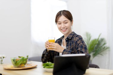 Beautiful woman eating fresh salad and watch favorite movies on tablet at the dining table, Vegetable salads are rich in vitamins and minerals, Fat-low-calorie and high-fiber diets, Healthy food, Appetizer.