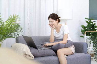 Beautiful Asian woman uses laptop to communicate work, Working from home at home happily, Freelancers work or learn in private rooms at home, Online communication, Home lifestyle.