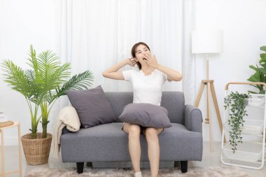Beautiful Asian woman sits lazily on the sofa, Preparing to sleep during the day, Girls' weekends are spent relaxing and lounging on their favorite sofas, Lazy or stretches, Comfort zone.