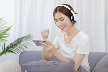 Woman play E-Sport games or streamers, Rejoices in victory, Male enjoying playing online games, Entertainment  or technology game trends, Fun holiday, Sitting on the sofa playing mobile games