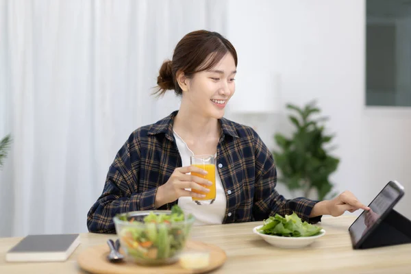 Beautiful woman eating fresh salad and watch favorite movies on tablet at the dining table, Vegetable salads are rich in vitamins and minerals, Fat-low-calorie and high-fiber diets, Healthy food, Appetizer.