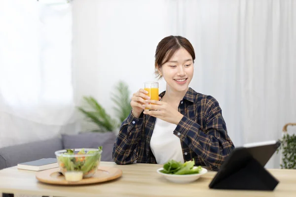 Beautiful woman eating fresh salad and watch favorite movies on tablet at the dining table, Vegetable salads are rich in vitamins and minerals, Fat-low-calorie and high-fiber diets, Healthy food, Appetizer.