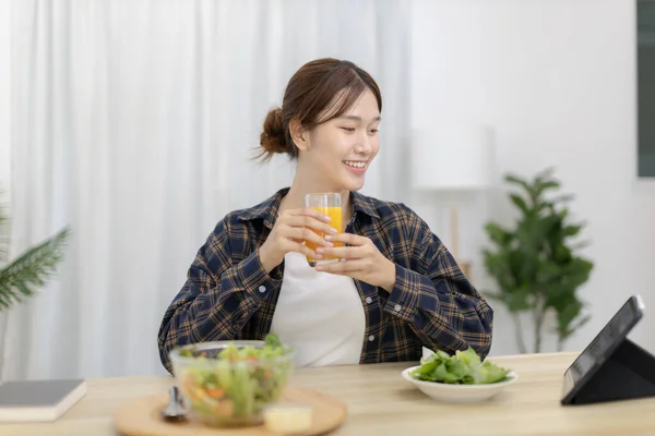 Beautiful woman eating fresh salad and watch favorite movies on tablet at the dining table, Vegetable salads are rich in vitamins and minerals, Fat-low-calorie and high-fiber diets, Healthy food, Appetizer.