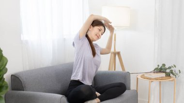 Güzel Asyalı kadın oturma odasındaki en sevdiği kanepeye uzanıyor, vücut ve zihin sağlığı hizmetleri meditasyon yoluyla rahatlama, sağlıklı egzersiz, sessiz oturma odası..