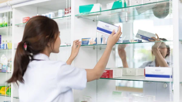 Pharmacist picks up pills on shelf from doctor\'s prescription, All kinds of generic household drugs and pharmaceutical products on the shelf , Administering medications as prescribed by the doctor.