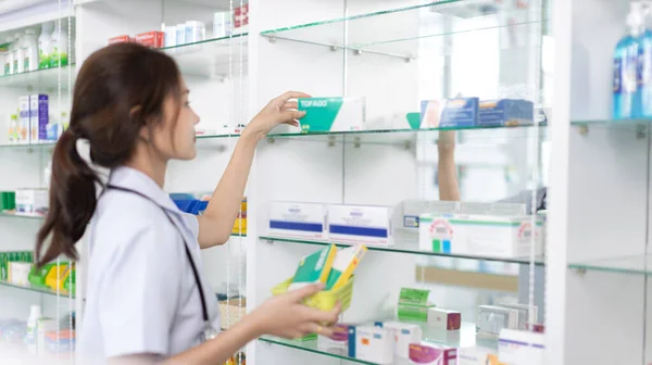 Pharmacist picks up pills on shelf from doctor\'s prescription, All kinds of generic household drugs and pharmaceutical products on the shelf , Administering medications as prescribed by the doctor.