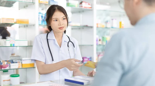 Credit card payment, Male patient pays by credit card to a pharmacist in a pharmacy, Get service at a community pharmacy , Pharmacist or cashier scanning medicinal products at checkout.