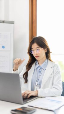 Çalışmak için dizüstü bilgisayar kullanan bir iş kadını, ofiste çalışan Asyalı bir kadın, evrak ve ekipmanlı bir muhasebeci, finansal işlemler için bilgisayarları kullanan bir muhasebeci..